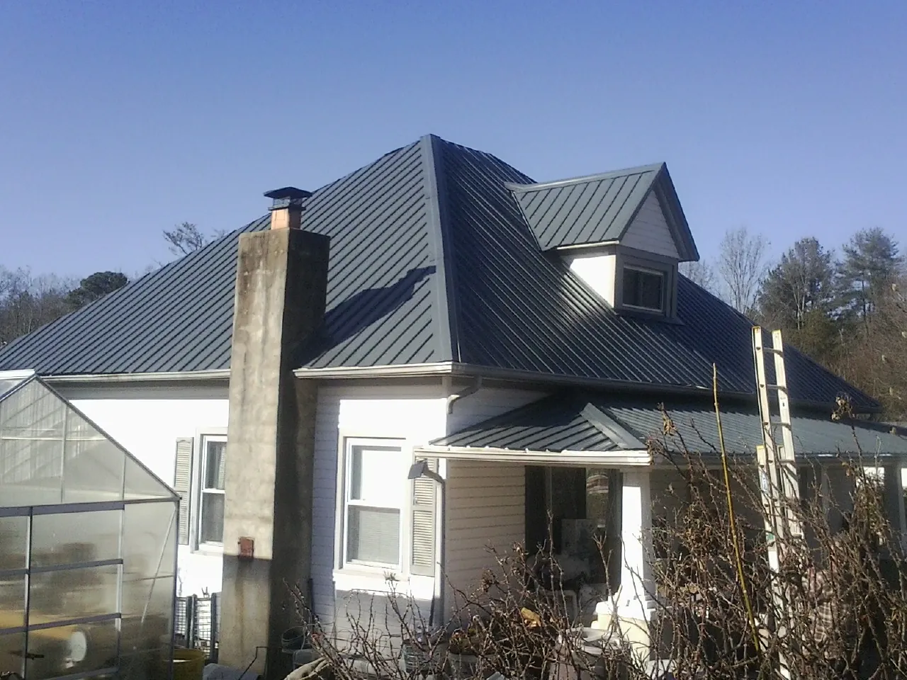 Dark blue standing seam metal roof on a white farmhouse with dormer — Slate & Tile Roof Repair by Roofing Brothers in Willows